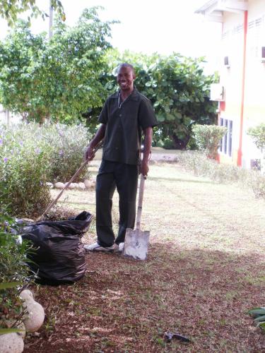 a man standing with a shovel and a trash bag at Pineapple Court Hotel in Ocho Rios
