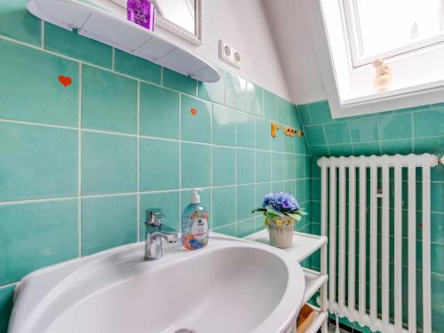 uma casa de banho com um lavatório branco e azulejos verdes em Cozy holiday apartment with balcony near the lake em Plön