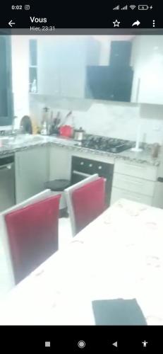 een keuken met een fornuis en 2 rode stoelen bij باهيه بيتش بشاطئ بوزينقه in Bouznika