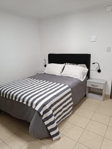 ein Bett mit einer schwarz-weißen gestreiften Decke in der Unterkunft Hermoso departamento en Rio Gallegos in Río Gallegos