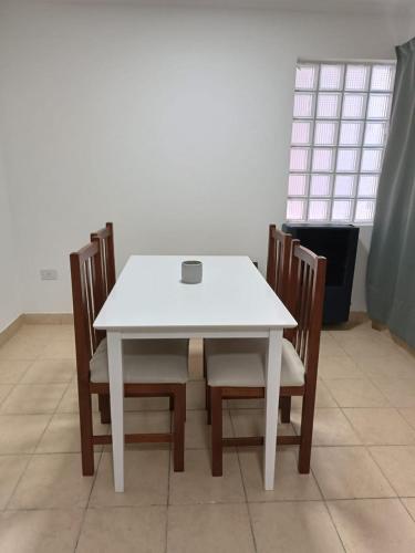 einen weißen Tisch und Stühle mit einem weißen Tisch und einem Fenster in der Unterkunft Hermoso departamento en Rio Gallegos in Río Gallegos