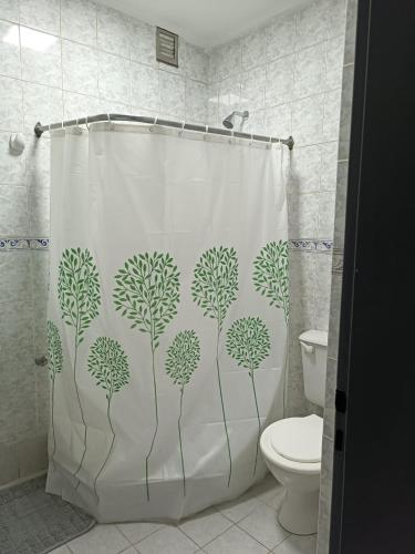einen Duschvorhang mit grünen Pflanzen im Bad in der Unterkunft Hermoso departamento en Rio Gallegos in Río Gallegos