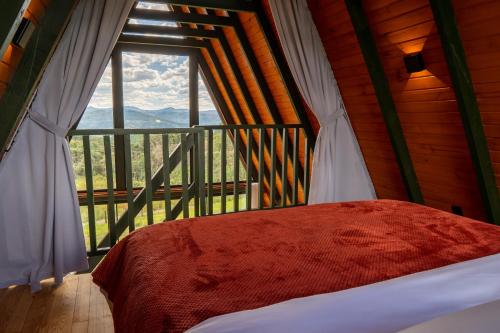 a bedroom with a bed and a large window at Altitude 1140 Urubici - Chalés in Urubici