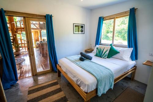 a bedroom with a bed with blue curtains and a window at Palayan Villa - Villa with views, garden and jacuzzi in El Nido