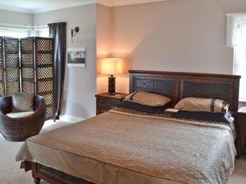 a bedroom with a large bed and a chair at Bengali in Ringford