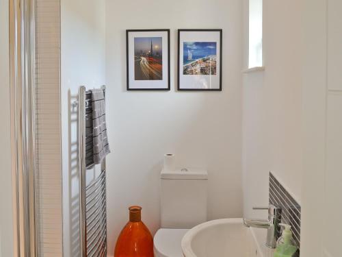 a bathroom with a toilet and three pictures on the wall at Bengali in Ringford