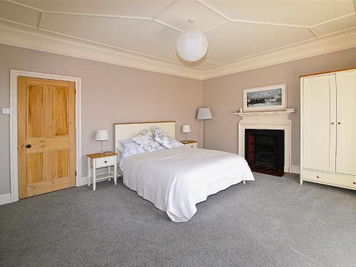 a bedroom with a white bed and a fireplace at Burford in Penzance