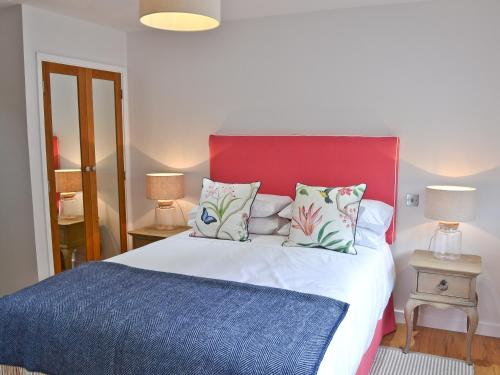 a bedroom with a large bed with a red headboard at The Wagon House in Luxulyan