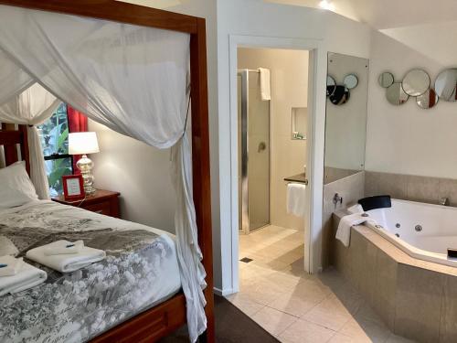 a bedroom with a tub and a bed and a bathroom at Linger a While Chalet on Gallery Walk with Spa, Fireplace, WiFi & Netflix in Mount Tamborine