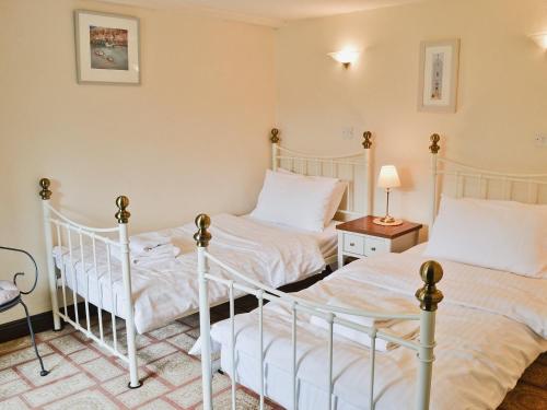 2 camas individuales en una habitación con mesa y lámpara en The Granary en Egloskerry