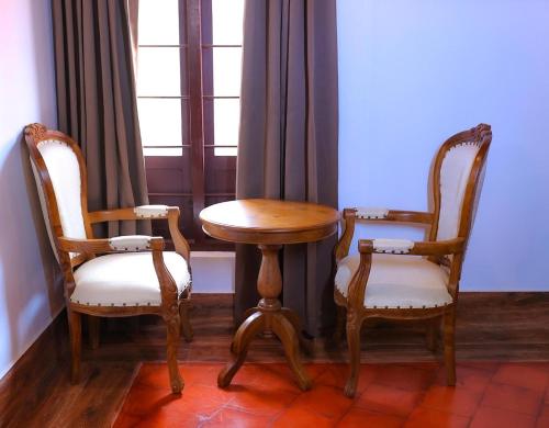 two chairs and a table in a room with a window at Heaven Inn Munnar in Munnar