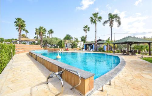 a swimming pool in a yard with palm trees at Beautiful Home In Pozzallo Rg in Pozzallo