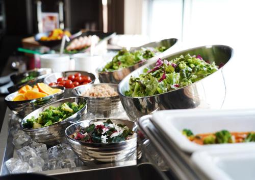 a buffet line with bowls of vegetables and other foods at APA Hotel TKP Keikyu Kawasaki Ekimae in Kawasaki
