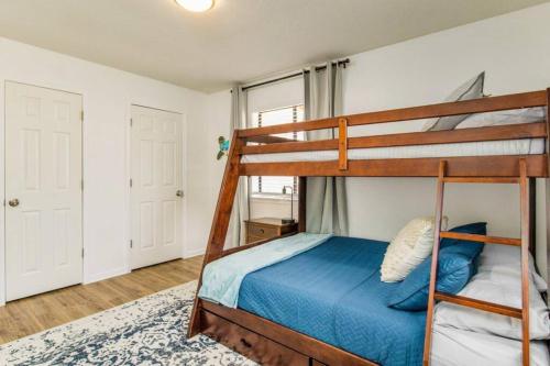 a bedroom with a bunk bed with a blue bedspread at Woodsy Retreat, steps to Bay - Hot tub! in Gulf Breeze
