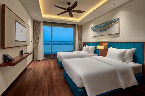 two beds in a hotel room with a ceiling fan at The Watson Premium HaLong Hotel in Ha Long