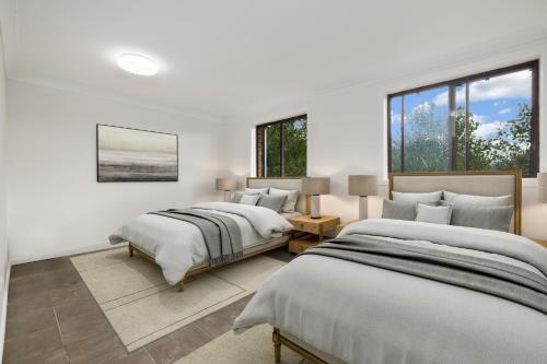 2 camas en una habitación blanca con ventanas en Alps Lakeview Lodge en Jindabyne