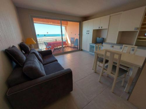 un salon avec un canapé et une table et une cuisine dans l'établissement Appartement 2 pièces climatisé en front de mer au Grau d'Agde avec terrasse et accès direct à la plage - FR-1-423-275, au Grau-dʼAgde