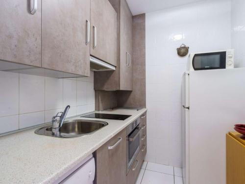 une cuisine avec un évier et un réfrigérateur dans l'établissement Appartement lumineux au port de plaisance, à 200m de la plage avec parking et commerces à proximité - FR-1-2-425, à Hendaye