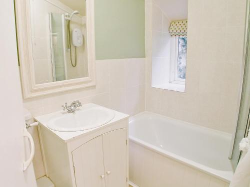 a white bathroom with a sink and a bath tub at Junipers - 28180 in Puncknowle
