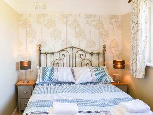 a bedroom with a bed with blue and white sheets at Dougies Retreat in Pevensey