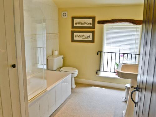 a bathroom with a toilet and a sink and a window at Woods Barn in Beckermonds