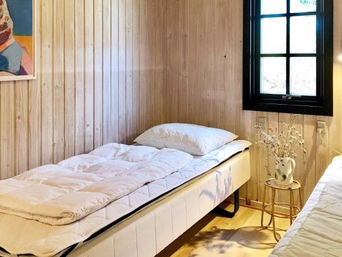 a bed in a room with a wooden wall at Holiday home Hadsund CXLIII in Hadsund