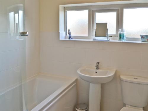 a white bathroom with a sink and a toilet at Riverbank Cottage in Althorpe