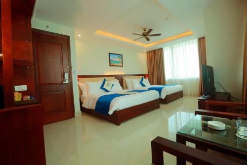 a hotel room with two beds and a table at Blue Wave Hotel in Cửa Lò