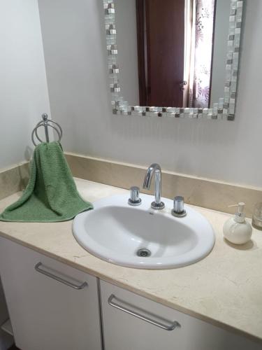 a bathroom sink with a green towel and a mirror at Temporario 2 habitaciones in Cañada de Gómez