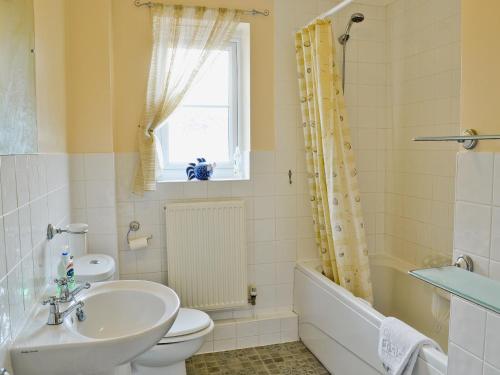 a bathroom with a sink and a toilet and a tub at Fairy Cottage in Old Newton