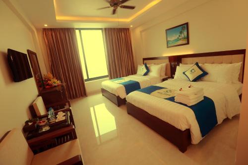 a hotel room with two beds and a window at Blue Wave Hotel in Cửa Lò
