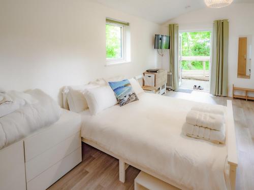 a white bedroom with a large bed and a window at Owl - Uk43447 in Hayle