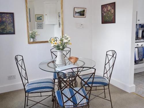 una mesa de comedor con sillas y un jarrón de flores en Keepers Cottage, en Helford Passage
