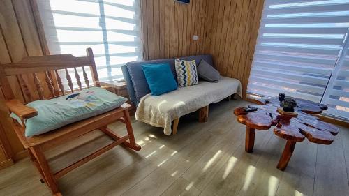 ein Wohnzimmer mit einem Sofa, einem Stuhl und einem Tisch in der Unterkunft Inversiones MM Gallardo SPA - Altos de Yaldad Cabañas in Quellón