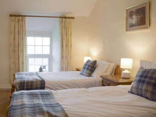 a bedroom with two beds and a window at Groudd Hall Cottage in Cerrig-y-Druidion