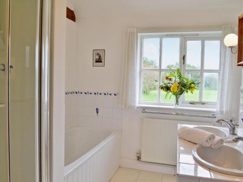 La salle de bains est pourvue d'une baignoire, d'un lavabo et d'une fenêtre. dans l'établissement Priory Barn, à Weald