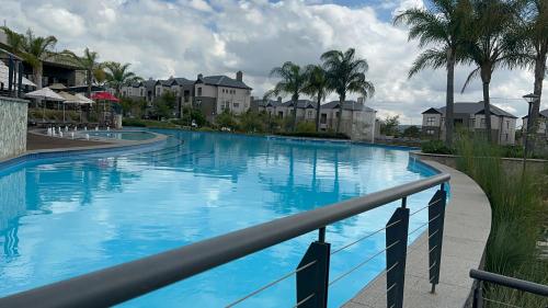 une grande piscine bleue avec des palmiers et des maisons dans l'établissement Fealathome Apartment, à Midrand