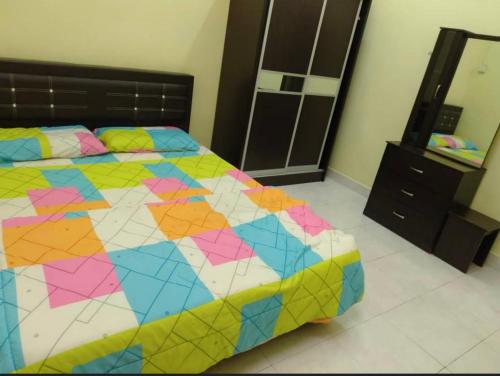 a bedroom with a colorful bed and a dresser at Raja Homestay Kluang in Kluang
