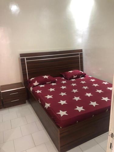a bed with a red comforter with white stars on it at Villa Al amine in Dakar