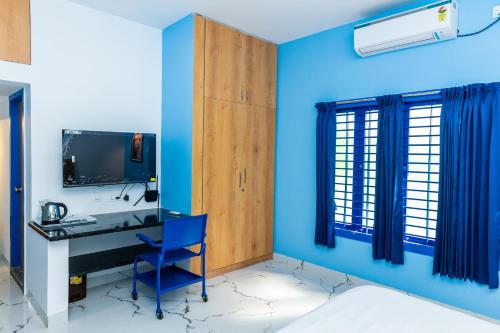 a room with blue walls and a desk with a computer at Panism Lifestyle in Auroville