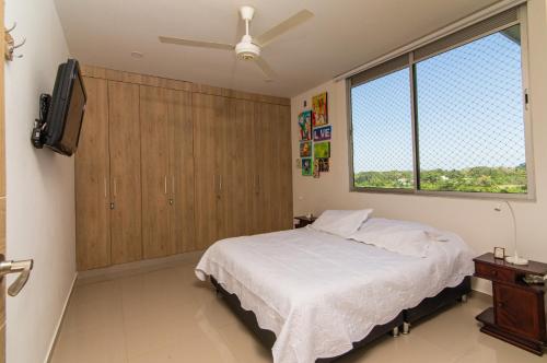 Schlafzimmer mit einem Bett, einem TV und einem Fenster in der Unterkunft Apartamento acogedor in Montería