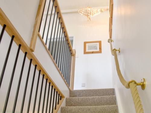 a staircase in a home with white walls and wooden railings at Fuggle in Ludham