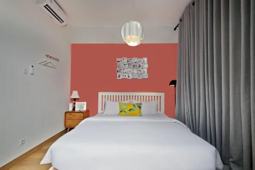 a bedroom with a white bed and a red wall at Roemah Renjana Rosie Makassar in Makassar