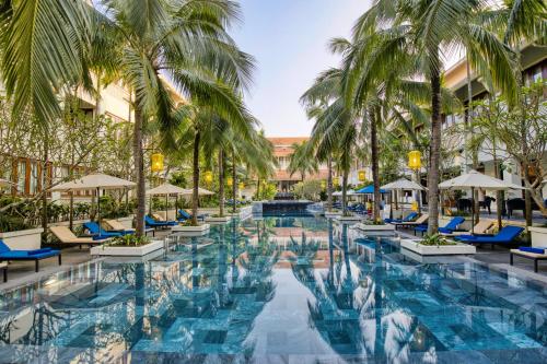 einen Pool im Resort mit Palmen und Stühlen in der Unterkunft Almanity Hoi An Resort & Spa in Hoi An