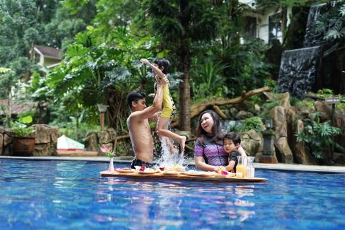 Eine Frau und zwei Kinder auf einem Floß im Schwimmbad. in der Unterkunft Safari Resort in Puncak