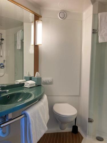 y baño con lavabo, aseo y espejo. en ibis Thornleigh, en Thornleigh