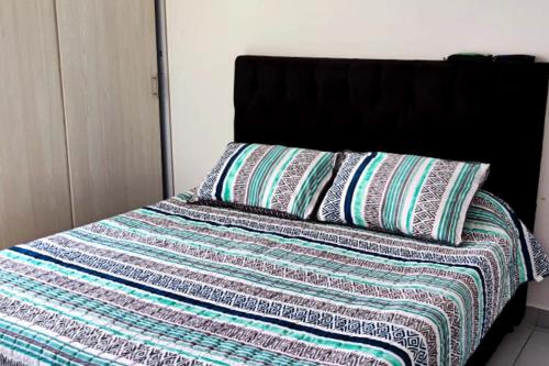 a bed with a quilt and two pillows on it at Apto en Girardot con Balcón, Piscina y Parqueadero in Girardot
