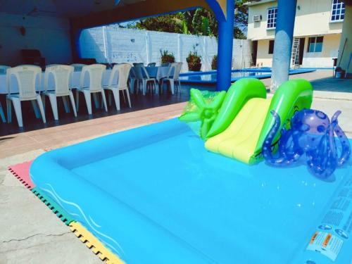 - un toboggan dans une piscine avec une table et des chaises dans l'établissement alberca Blass, à Coatzacoalcos