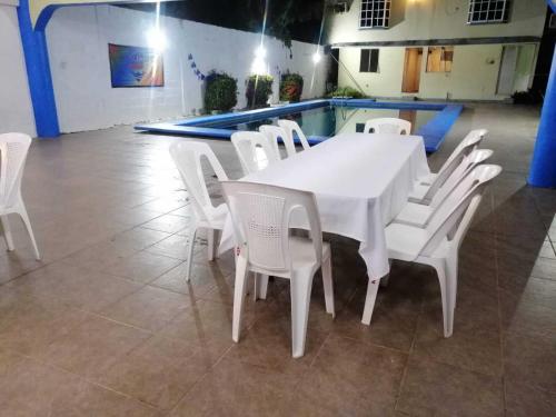 una mesa blanca y sillas en una habitación con piscina en alberca Blass en Coatzacoalcos