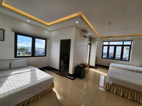 a large room with two beds and large windows at Phụng Hoàng Vũ in Bạc Liêu